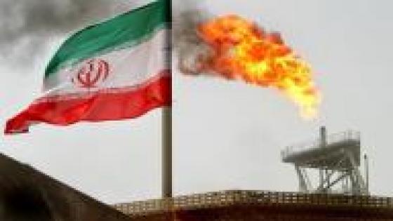 صورة من أرشيف رويترز للعلم الإيراني بجانب شعلة غاز بحقل نفطي في إيران.